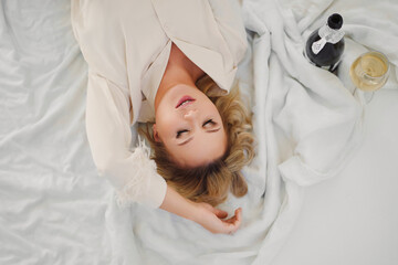 top view. blonde in delicate pajamas in bed with a champagne