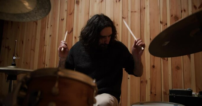 Emotional musician with drumsticks playing drums and cymbals in slow motion