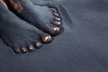 Photo of dirty woman bare feet in black sand. People relaxation, fun and walking barefoot by black...