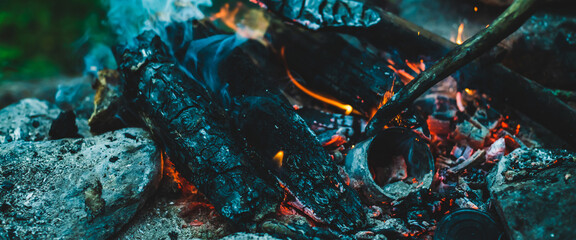 Vivid smoldered firewoods burned in fire close-up. Atmospheric warm background with orange flame of...