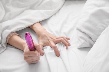 Woman with vibrator in bed, closeup