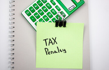 TAX PENALTY text concept on paper next to calculator. Financial concept about punitive taxes.
