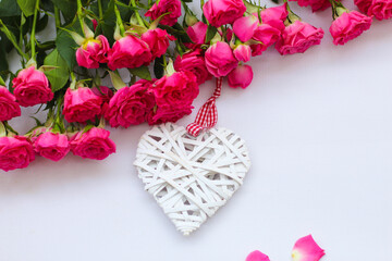 Decorative white heart made of vines, Valentine's Day on the background of a bouquet of roses.