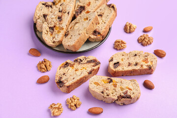 Plate with delicious biscotti cookies  and nuts on lilac background