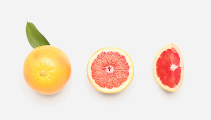 Composition with whole and cut grapefruits on white background
