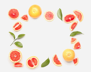 Frame made of juicy grapefruit pieces and plant leaves on white background