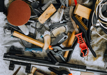 A pile, many household tools are scattered randomly on the table in the mechanic's workshop....