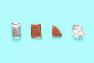 Composition with pieces of tasty chocolate and foil ball on color background