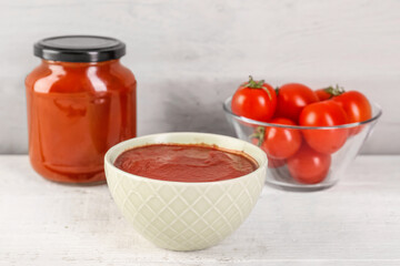 Bowl of tasty tomato paste on white grunge background