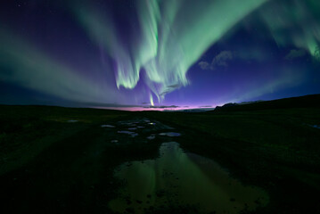 Full sky aurora borealis reflecting in road puddles, Skaftafell Iceland