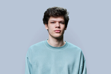 Fototapeta premium Headshot portrait of young male in casual sweatshirt, on gray background
