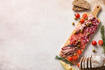 Wooden board with assortment of tasty deli meats on light background