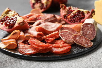 Slate plate with assortment of tasty deli on grunge background, closeup