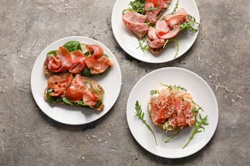 Plates of tasty bruschettas with ham on grunge background