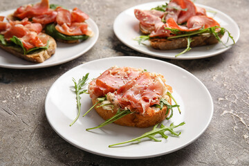 Plates of tasty bruschettas with ham on grunge background