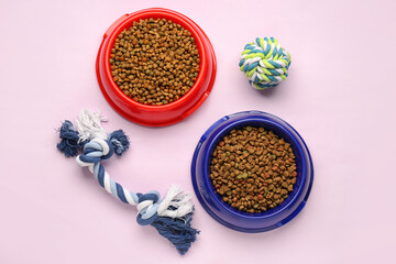 Obraz na płótnie Canvas Bowls of dry pet food and toys on color background