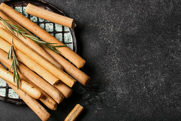 Plate with tasty Italian Grissini on dark background, closeup