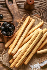 Board with tasty Italian Grissini on wooden background