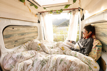 woman reading in the camper van, caravan, at sunset, book, woman smiling in nature