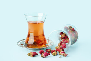 Glass of Turkish tea and dry roses on light blue background