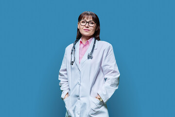 Portrait of confident mature female doctor on blue background