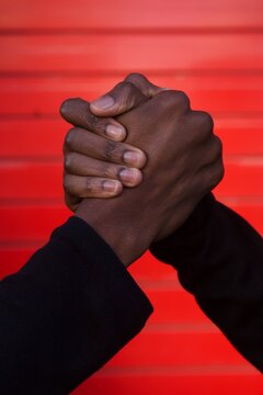 Two hands locking in front of red wall