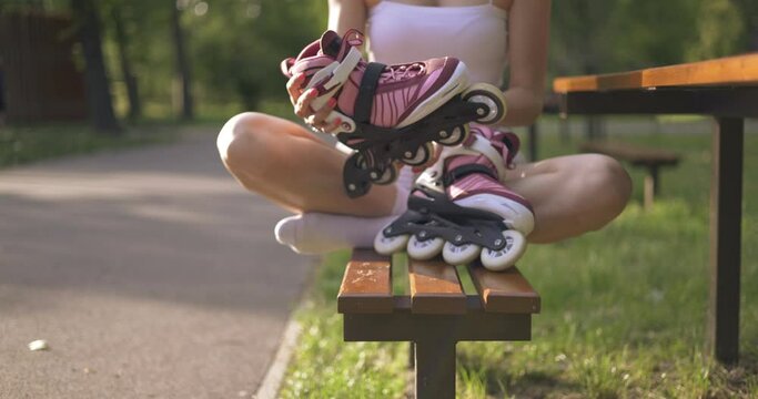 Girl sits on park bench with crossed legs holding roller skates