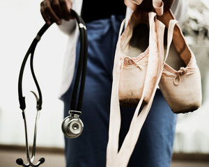 Person holding ballerina shoes and stethoscope
