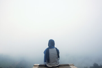 Back view of woman wearing hijab sitting on dock