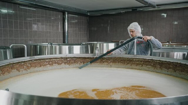 A brewery worker uses a vacuum cleaner to collect foam from beer that is brewed in huge steel tanks at the brewery.