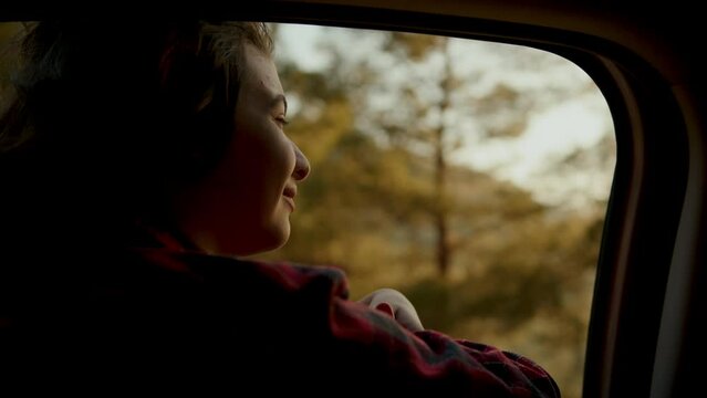 School age girl smiling carelessly and enjoying journey. Happy family travel concept. Child leaned out of car window smiling with pleasure