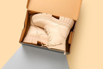 Cardboard box with stylish shoes on color background