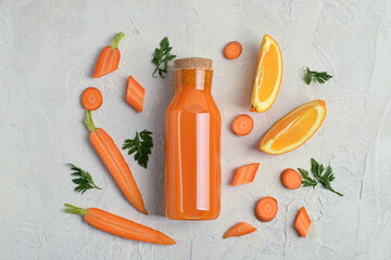 Glass bottle of tasty carrot juice on light grunge background