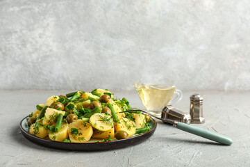 Plate of tasty Potato Salad with vegetables on grey background