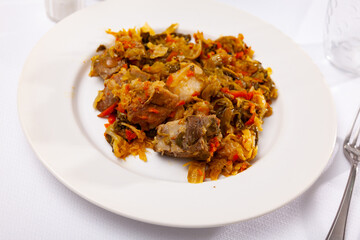 Close up of plate of braised sauerkraut with fried pork meat served on white plate