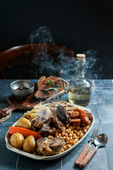 Cocido Madrileño, a traditional Spanish meal, chickpea-based stew from Madrid                          blue ceramic tile background