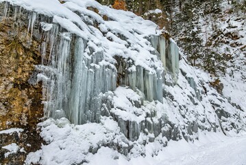 Fototapeta na wymiar Snow covered frozen waterfall on an Alpine hillside