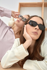 Two beautiful fashion girls in glasses and modern clothes, posing with glasses at the camera, image of stylish young girls in glasses
