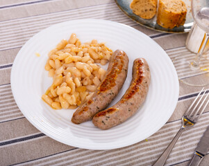 Botifarra amb mongetes, representative dish of Catalan home cooking - traditional fried botifarra sausage served with cooked white beans..