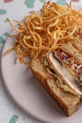 Manos sosteniendo un sándwich de potobelo y coleslaw con papas fritas. Gastronomía vegana