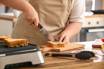 Obraz premium Woman preparing delicious sandwiches near modern electric grill on kitchen counter