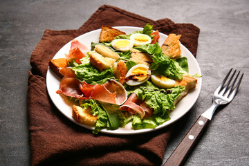Plate of delicious salad with boiled eggs and jamon on black grunge background
