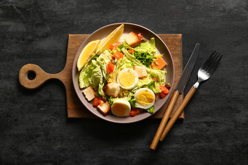 Plate of delicious salad with boiled eggs and salmon on black grunge background