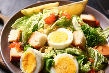 Plate of delicious salad with boiled eggs, croutons and salmon, closeup
