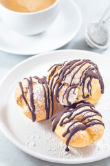 Profiteroles with whipped cream and chocolate filling, covered with melted chocolate, with coffee