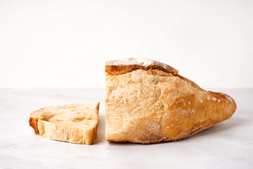 Sliced loaf of fresh bread on white table