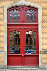 Fototapeta na wymiar View of brick building with red wooden door