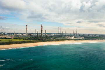 Aerial drone photo of industrial power plant by the sea. Industrial Plant at Sunset with Smoke coming from the Chimney. Electricity power plant by the sea. Aerial view on a large thermal power plant.