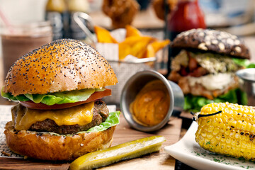 Gourmet cheeseburger with poppy seed freshly baked bun, dill pickles, spicy sauce, and sweet yellow...