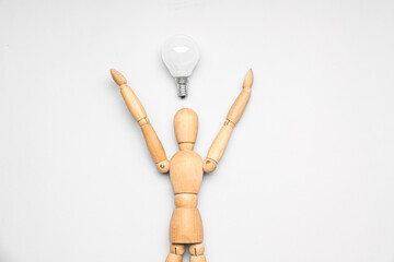 Wooden mannequin with light bulb on light background. Insight concept